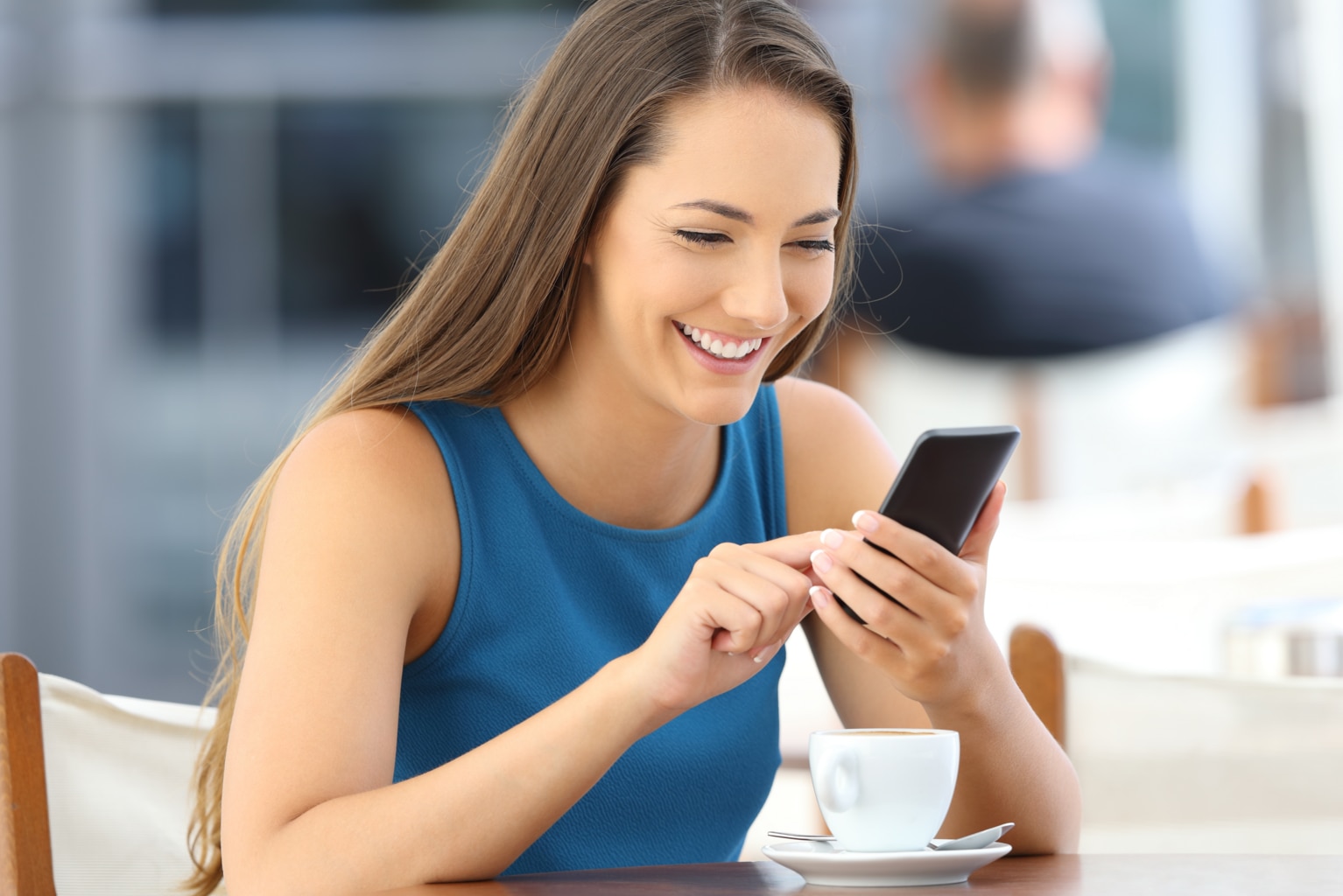 Happy woman using a smart phone alone sitting in a bar terrace