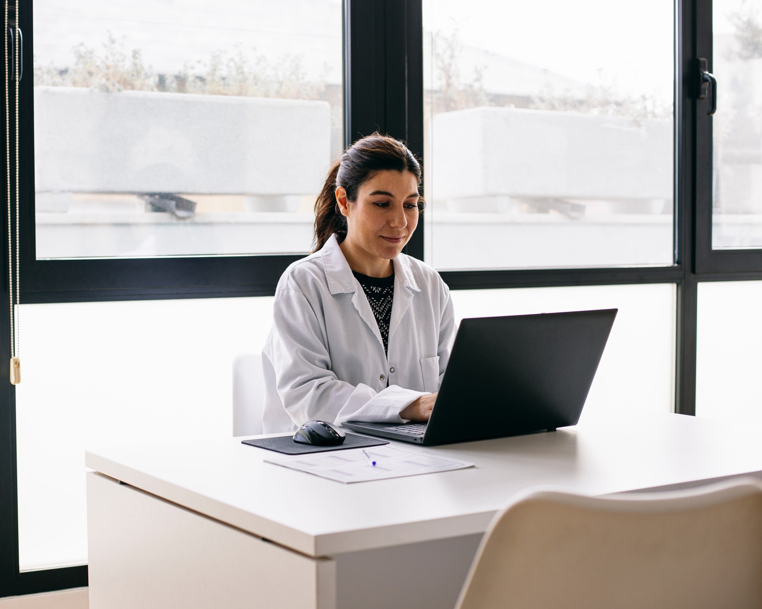 Doctor sitting at desk in medical practice using laptop