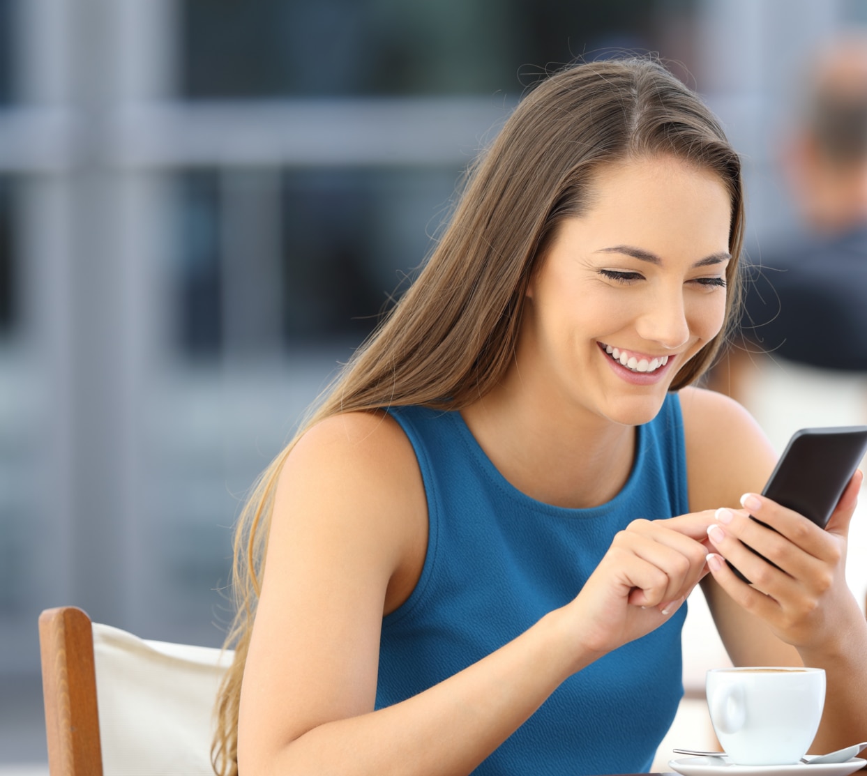 Happy woman using a smart phone alone sitting in a bar terrace