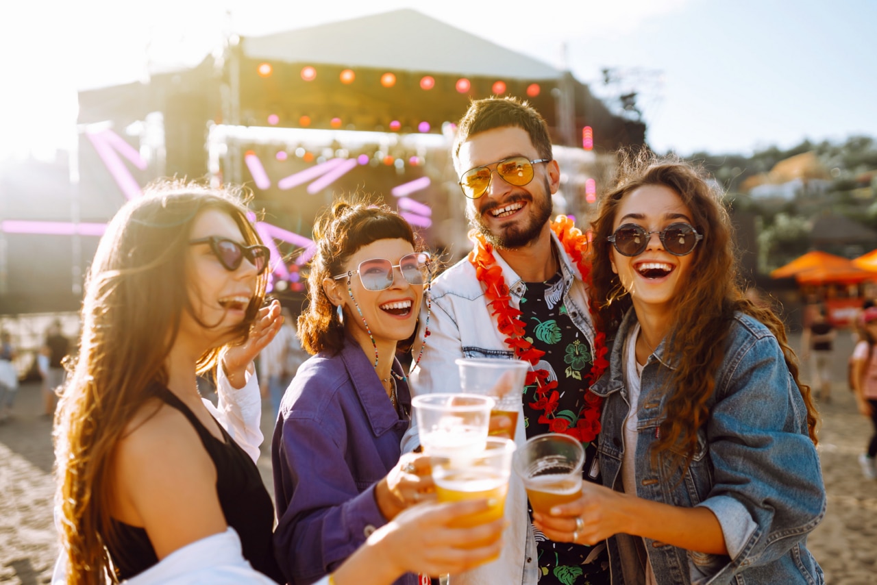 Young happy friends drinking beer and having fun at music festival together. Beach party, summer holiday, vacation concept. Friendship and celebration concept.; Shutterstock ID 1724134180; purchase_order: -; job: -; client: -; other: -