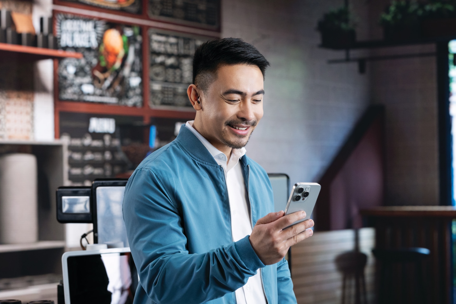 En man som kollar mobiltelefonen på ett café 