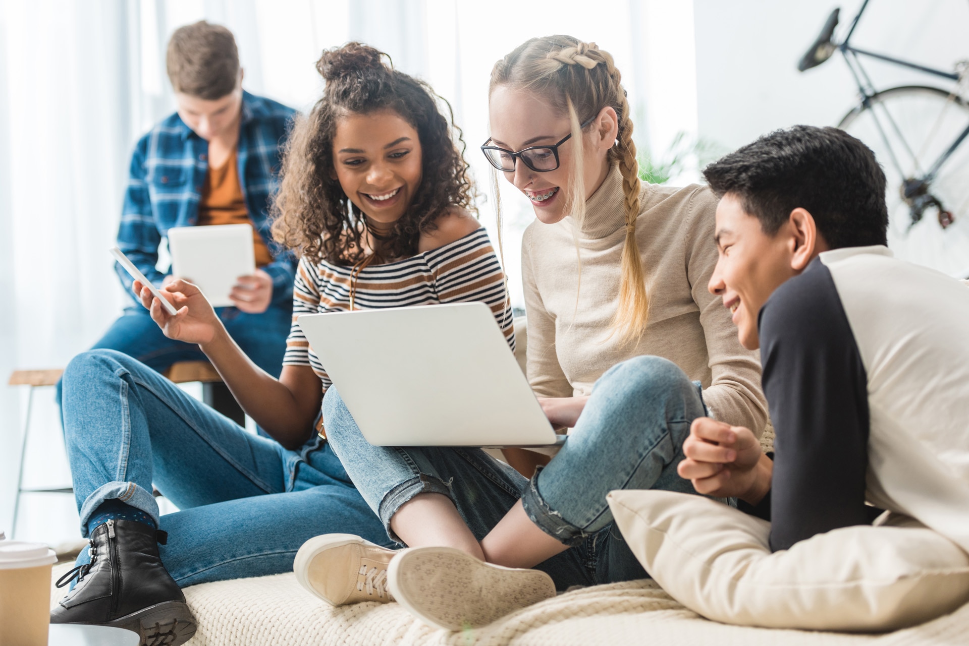 A group of multicultural teens looking at a laptop on a sofa