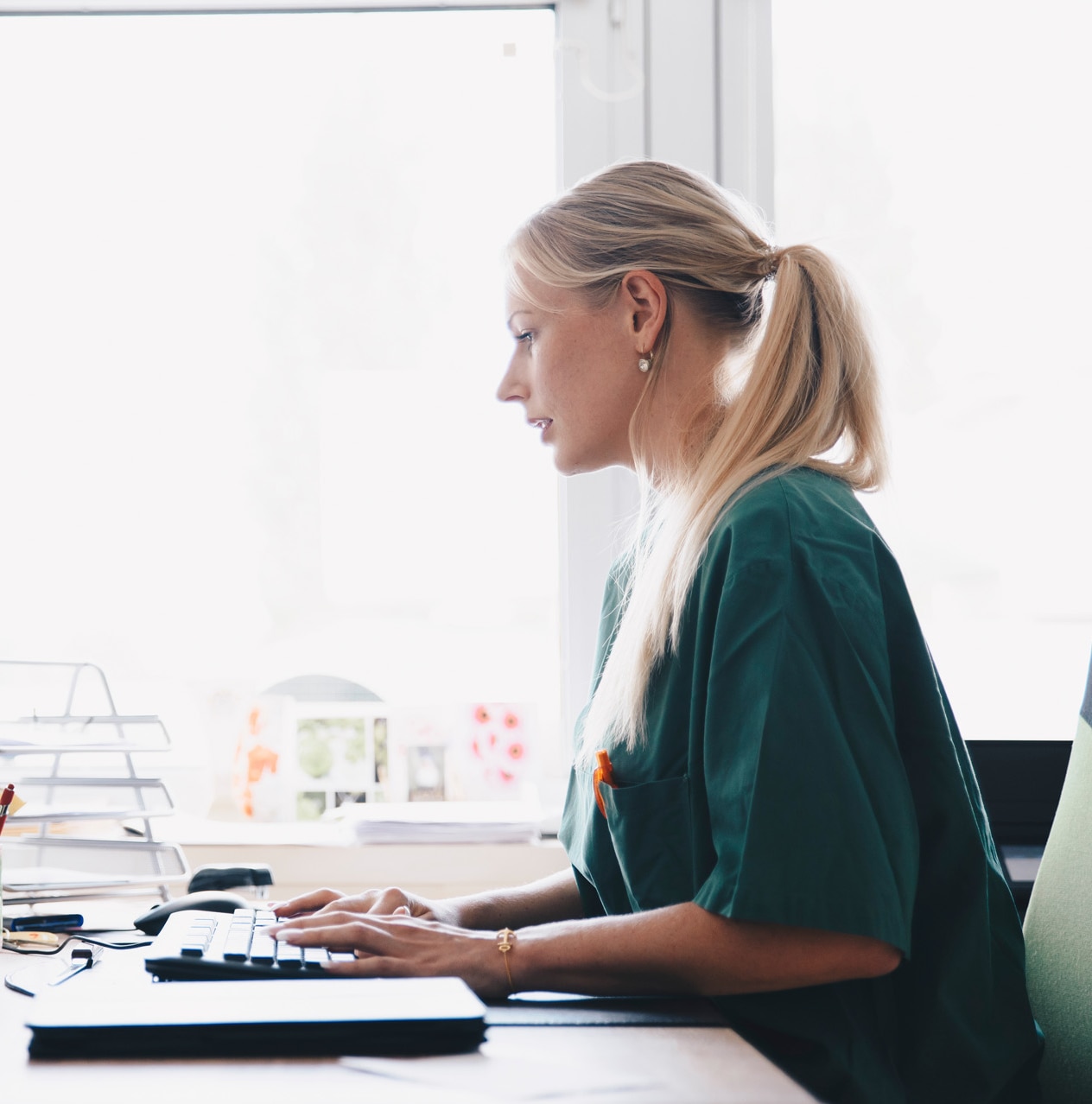 Female doctor filling patient data in front of a desktop.