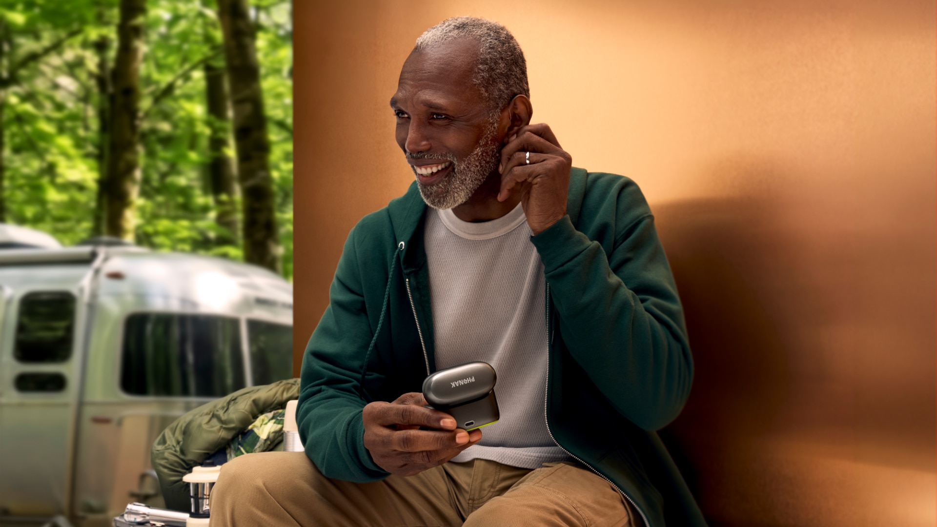 Person using Phonak Audéo™ EON R  hearing aids with a smartphone outdoors.