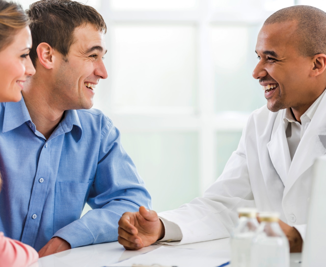 Cheerful male doctor communicating with young couple in his office.