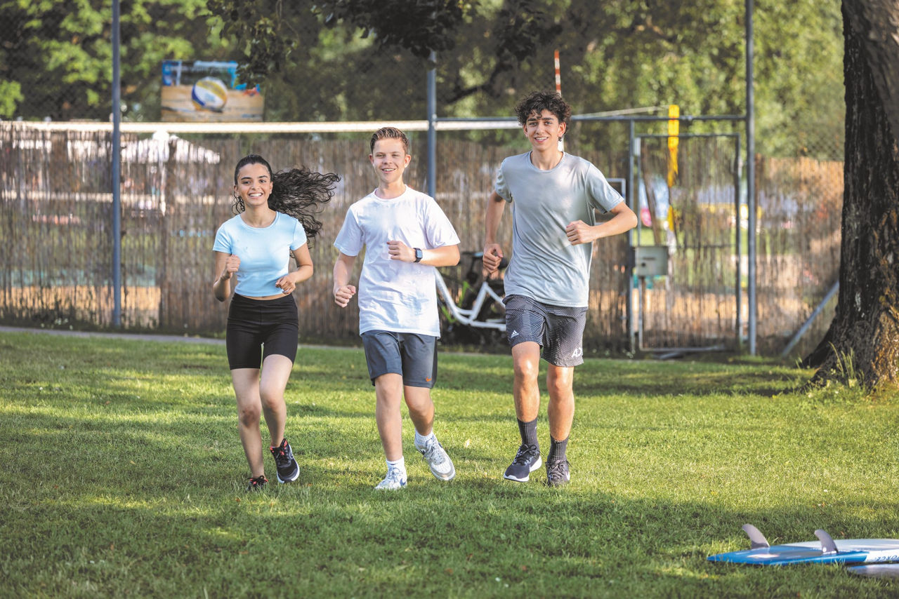 A group of teenagers running in a park