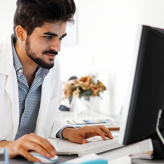 Hearing care professional working at a computer in a clinic.