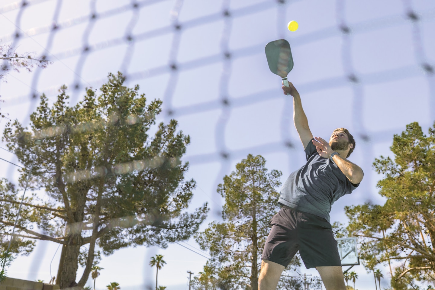 Man jumping to hit yellow pickleball
