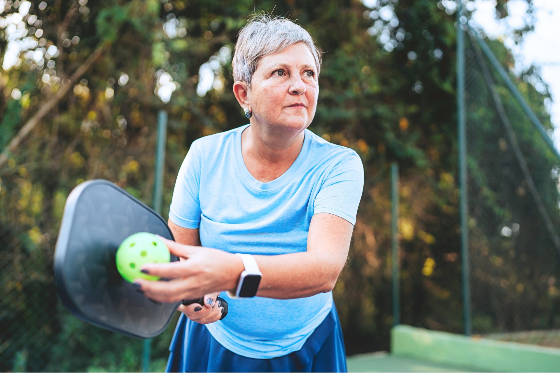 Man playing pickleball wearing white shirt and sunglasses