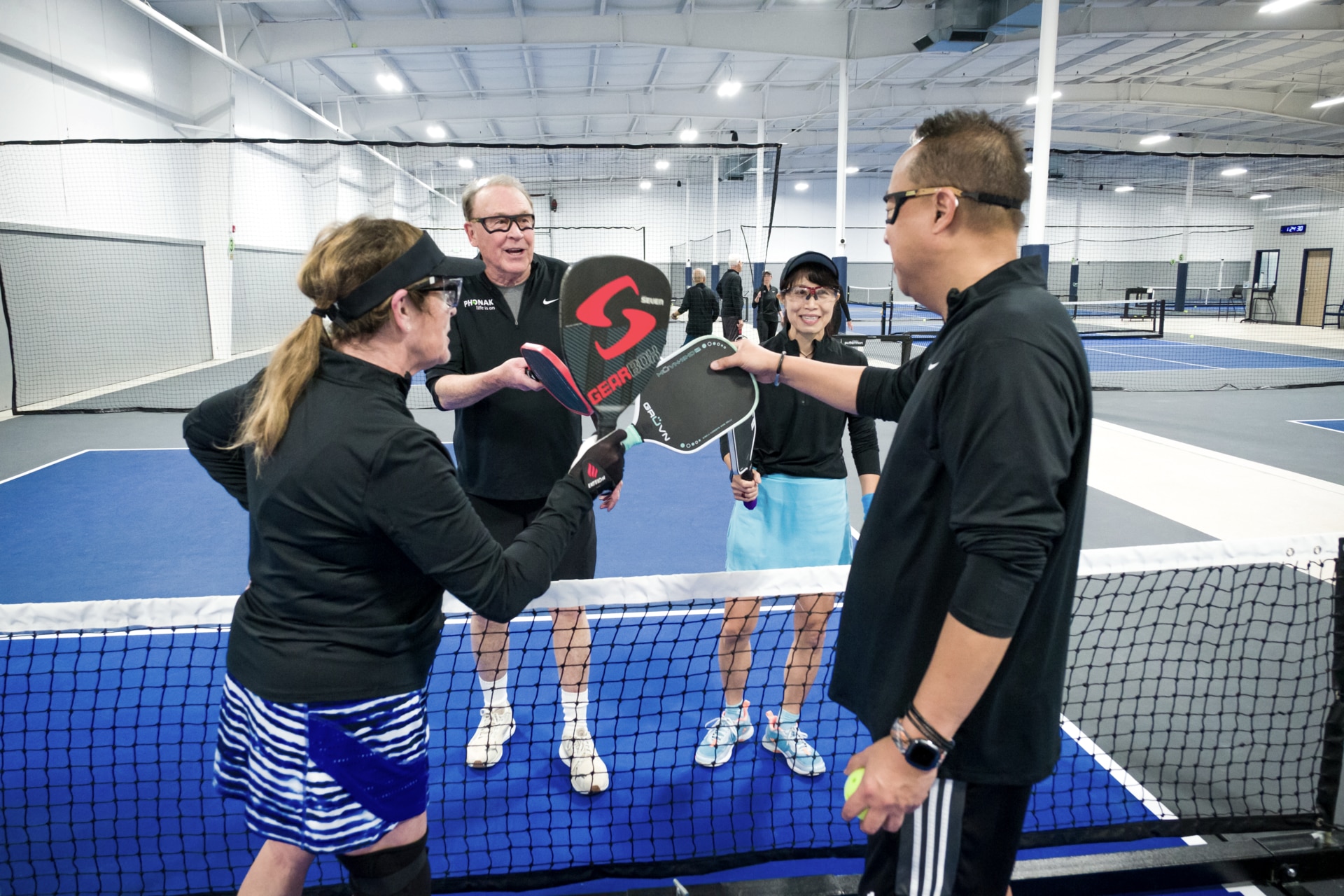 Pickleball teams greeting each other by tapping paddles