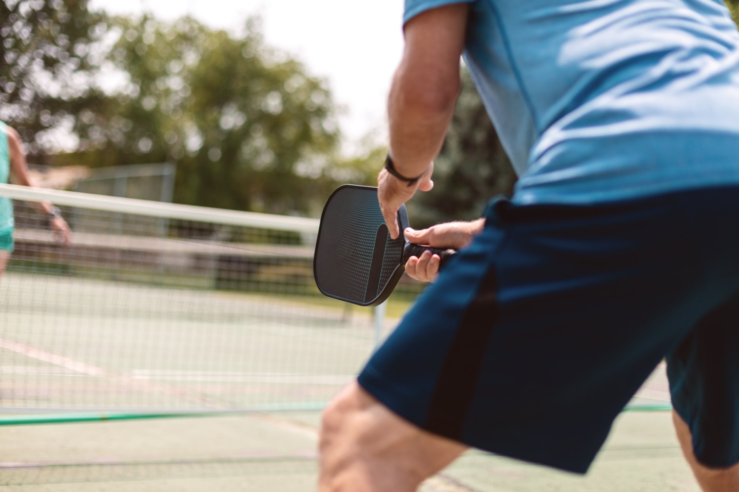 Man playing pickleball wearing blue shorts and shirt