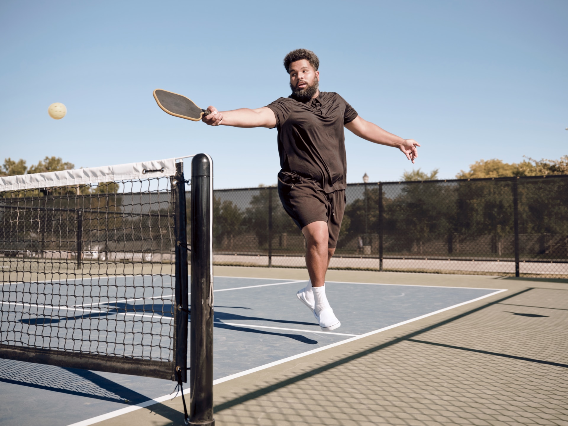 Man jumping to hit pickleball