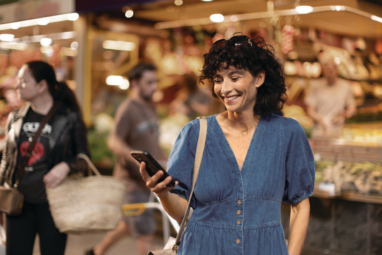 A middle-aged woman looking at her phone during shopping, smiling