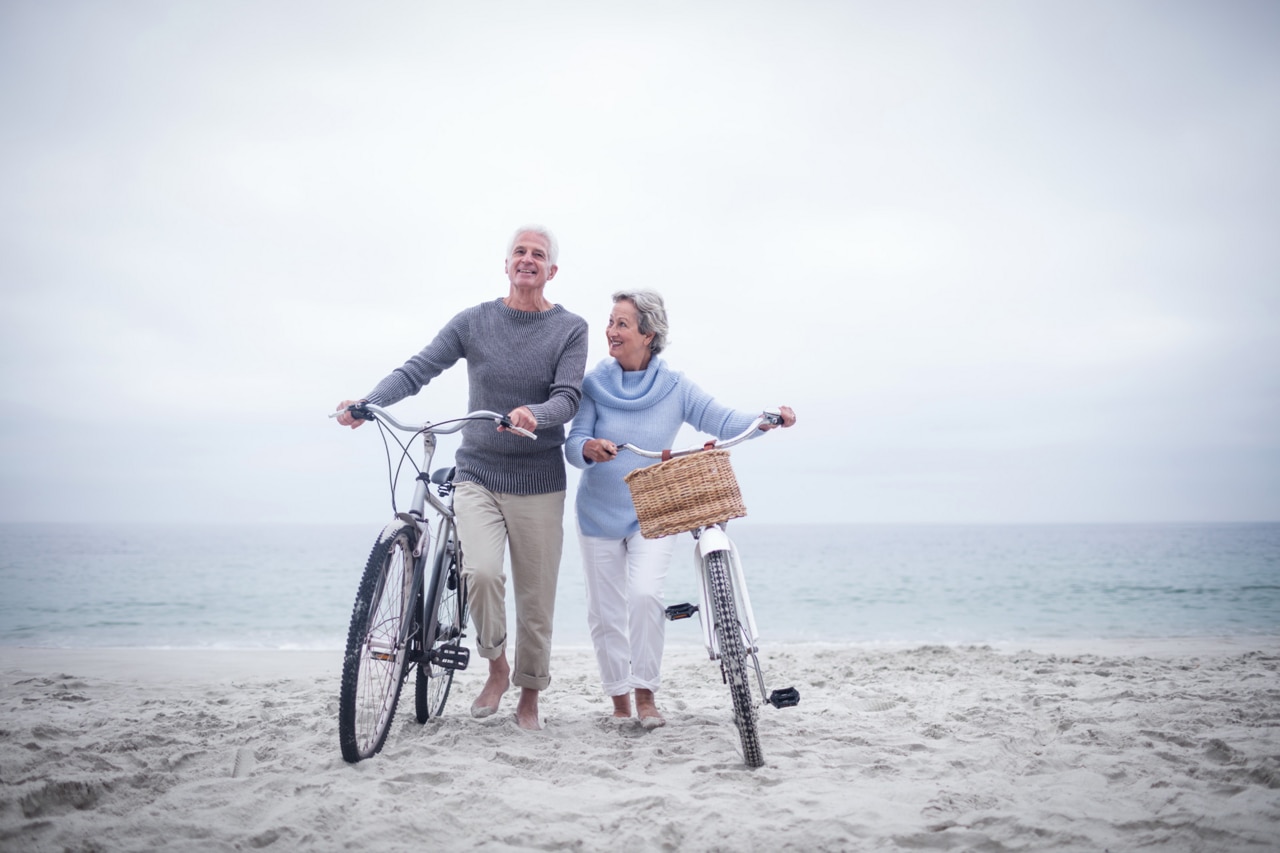 Senior couple having ride with their bike on the beach; Senior couple having ride with their bike on the beach;