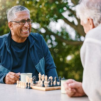 Chess, nature and retirement with senior friends playing a boardgame while bonding outdoor during summer. Park, strategy and game with a mature man and friend thinking about the mental challenge