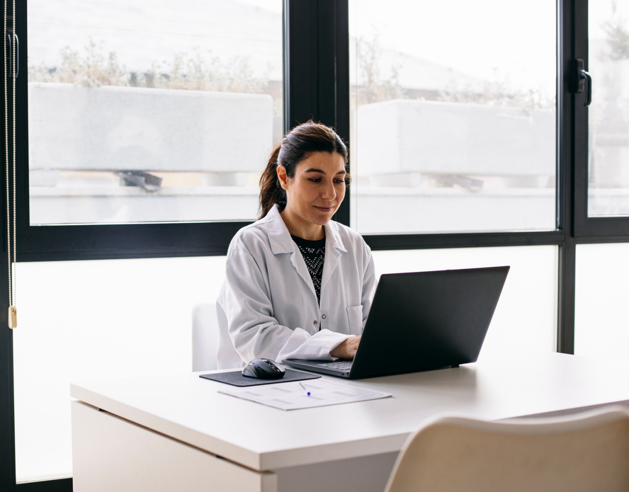 Doctor sitting at desk in medical practice using laptop