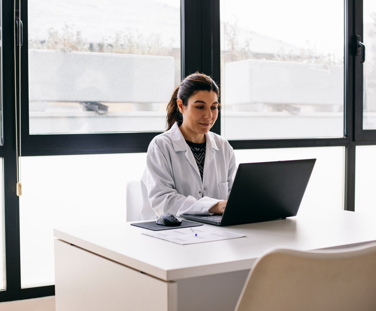 Doctor sitting at desk in medical practice using laptop