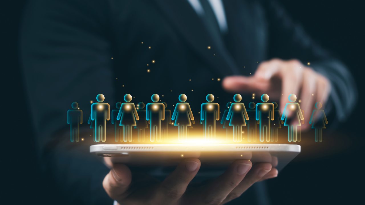 A hand hovering over a tablet with multiple illustrated silhouettes projected