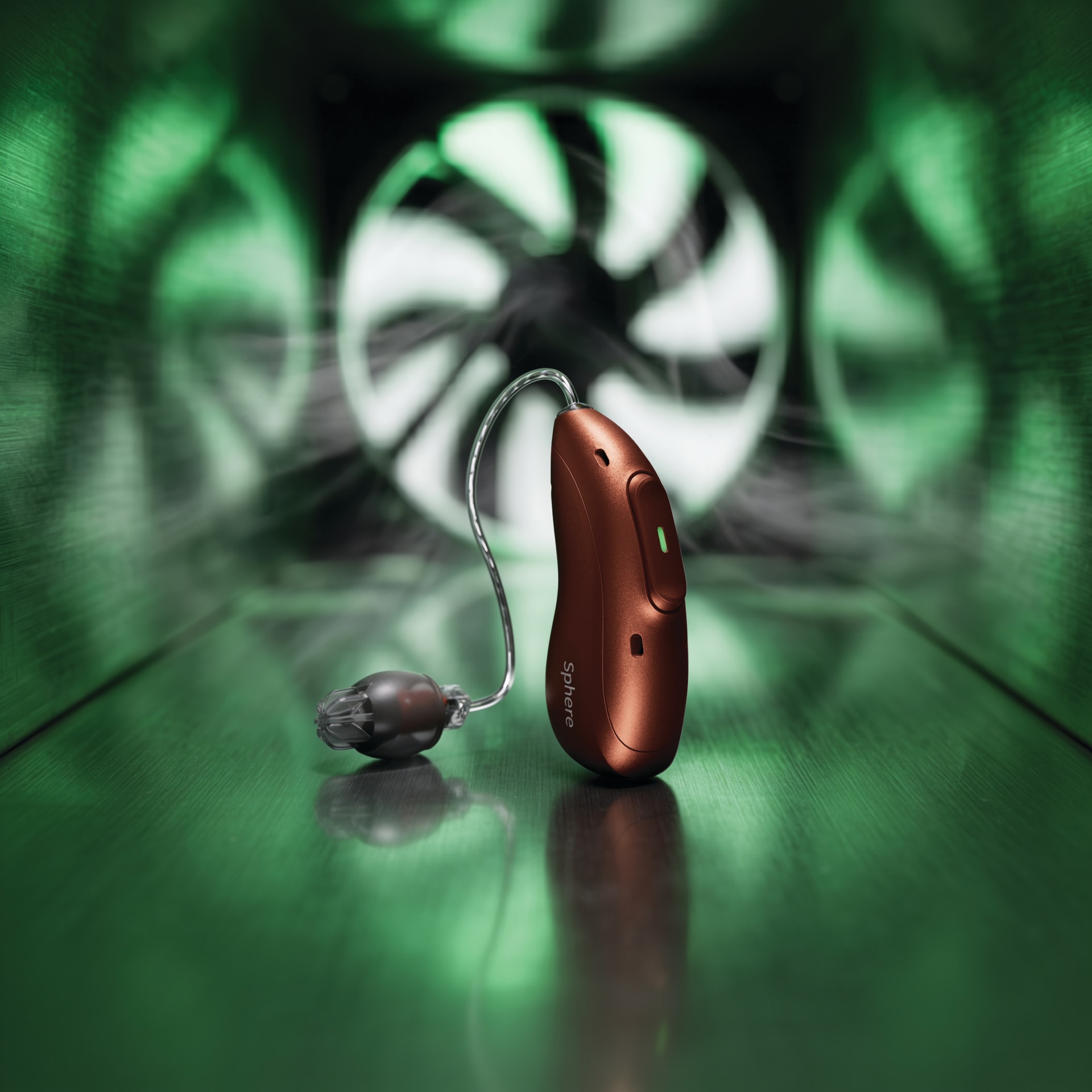Audeo EON hearing aid with tubing and earmold on a glossy green surface, set against a green tunnel with a white spiral light in the background.
